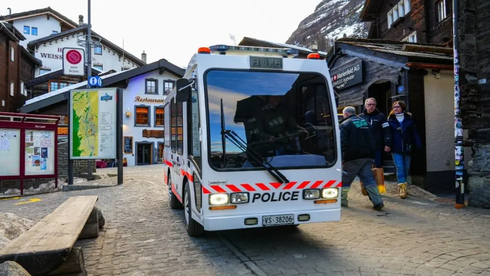 Zermatt, Switzerland - Feb 19, 2024 : Police vehicle in the city center of the ski resort of Zermatt in the Canton of Valais, Switzerland - Narrow electric car Jumbolino in a car-free town of the Swis