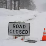 "Road Closed" sign during atmospheric river winter storm event in the Sierra Nevada mountains.