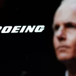 Logo of the Boeing Company^ with CEO Dave Calhoun in the background