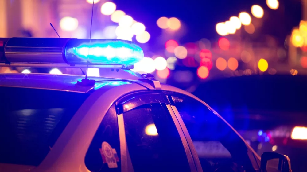 Blue light flasher atop of a police car. City lights on the background.