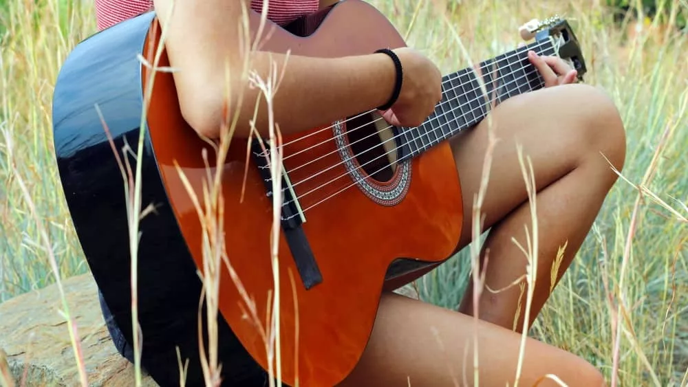 female country artist playing guitar outdoors