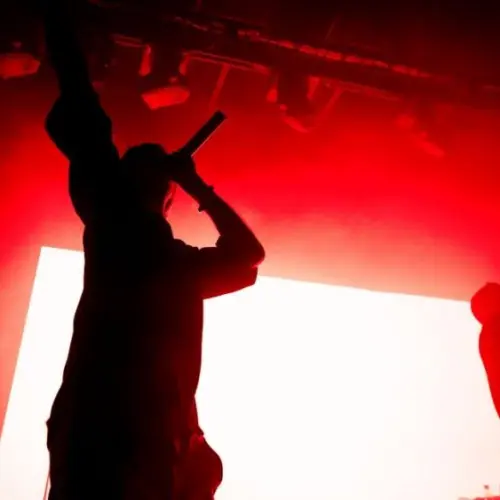 Silhouettes of two singers on the stage. Music band on the stage^ red lightning. Rappers pulling out their hands on the stage.