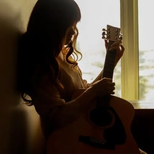 Silhouette of a young woman playing guitar alone in the dark