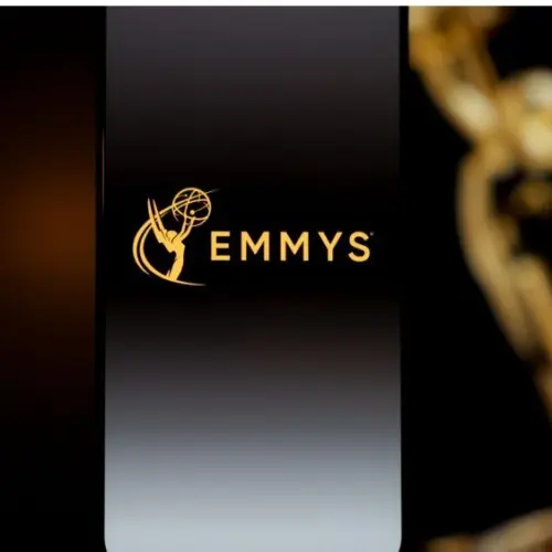Emmys logo displayed on a smartphone screen with a blurred gold award statuette in the background^ television industry awards and digital streaming concept. Kaunas^ Lithuania - 2026 March 24