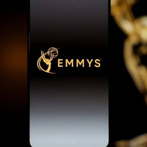 Emmys logo displayed on a smartphone screen with a blurred gold award statuette in the background^ television industry awards and digital streaming concept. Kaunas^ Lithuania - 2026 March 24