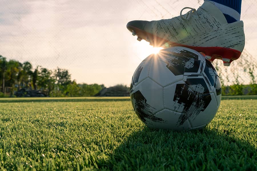 athlete-standing-with-ball-on-football-field-during-sunrise-soc