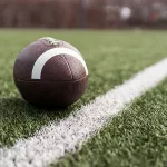 american-football-ball-on-green-grass-field-background