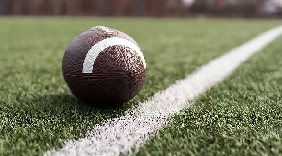 american-football-ball-on-green-grass-field-background