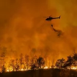 Fire fighting helicopter carry water bucket to extinguish the forest fire.