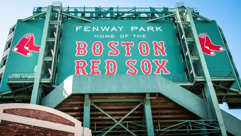 View of the historic architecture of the Fenway Park Stadium showcasing its signs^ brick walls^ statues^ and the famous green color and red letters of the red sox. Boston^ MA^ USA - March 10^ 2023