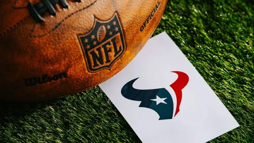 Houston Texans NFL team Logo and American football ball on Green Grass. HOUSTON^ USA^ FEBRUARY 10^ 2025