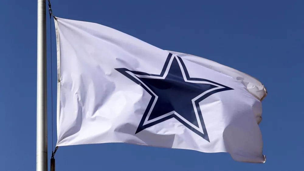 Dallas Cowboys flag flies in front of the AT&T Stadium located in Arlington^ Texas on March 14^ 2014. AT&T Stadium is home to the Dallas Cowboys of the NFL.