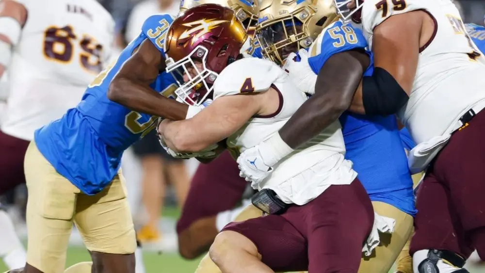 Arizona State running back Cam Skattebo #4 runs against UCLA defensive line Gary Smith III #58 and defensive back Alex Johnson #36 during an NCAA college football game^ Nov. 11^ 2023^ in Pasadena.