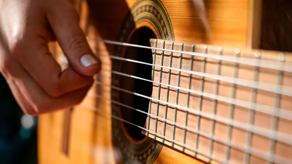 Closeup of hand of woman plays an acoustic guitar.