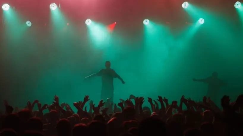 Rap singer performing on concert in music hall. Silhouette of rapper singing on stage in night club. Popuar hip hop music festival. Crowd of fans partying on dance floor