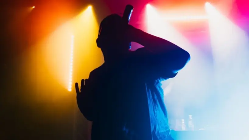 A silhouette of a singer on the stage. Good-looking background^ bright stage lights.