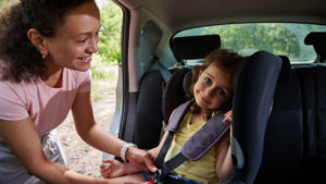 woman-puts-her-daughter-in-the-child-car-seat-and-fastens-the-child-with-a-seat-belt-safety-of-traveling-in-a-car-with-children