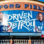 Closeup of "Ford Field" Detroit Lions' football field stadium's exterior facade brand and logo signage on a sunny day.