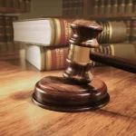 Wooden gavel on the judge's bench with a backdrop of law books