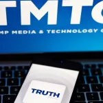 Truth Social app logo seen on the smartphone and blurred TMTG logo on the laptop.