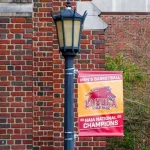 "2022 NAIA Men's Basketball National Champions" banner hangs from lamp post at Louise C. Thomas Hall at Loyola University