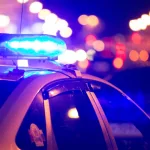 Blue light flasher atop of a police car. City lights on the background.