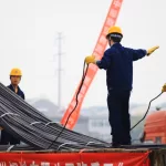 China's eastern city of Jiujiang^ workers in the steel building materials market hoisting steel. China's steel demand slump triggered the global steel industry downturn.