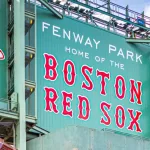 view of the historic architecture of the Famous Fenway Park Stadium in Boston^ MA^ USA showcasing its huge sign^ old brick walls^ and entrances on Lansdowne street. Boston^ MA^ USA - March 1^ 2023