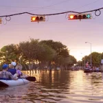 Working traffic lights over flooded Houston streets and boats with people at sunset. Texas^ USA
