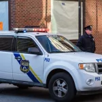 A uniformed Philadelphia Police officer stands beside a police vehicle. PHILADELPHIA^ PA - JANUARY 1^ 2015