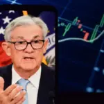 Federal Reserve (Fed) Chair Jerome Powell is visible. In the background^ an inflation rate chart is displayed.