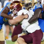 Arizona State running back Cam Skattebo #4 runs against UCLA defensive line Gary Smith III #58 and defensive back Alex Johnson #36 during an NCAA college football game^ Nov. 11^ 2023^ in Pasadena.