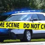 Sheriff Department vehicle with emergency lights on behind Crime Scene tape