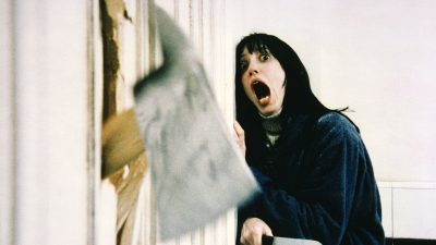 Woman scared watchin an axe go through a door