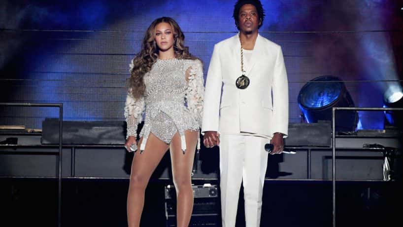 Jay-z and Beyonce holding hands on stage wearing all white