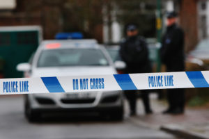 LONDON - DECEMBER 27: Police tape is pictured as police officers stand guard outside of a house in Edgeware on December 27, 2007 in London, England. A man is facing charges after a police officer was killed on duty after being called to a domestic row at an address in North London.