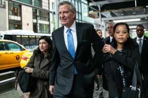 Bill de Blasio, mayor of New York City, center, departs after speaking during a 'Green New Deal' rally in the lobby of Trump Tower in New York, U.S., on Monday, May 13, 2019. De Blasio's Green New Deal aims to ban glass and steel skyscrapers, saying those buildings are much less energy efficient than their brick and concrete counterparts and contribute more to global warming.