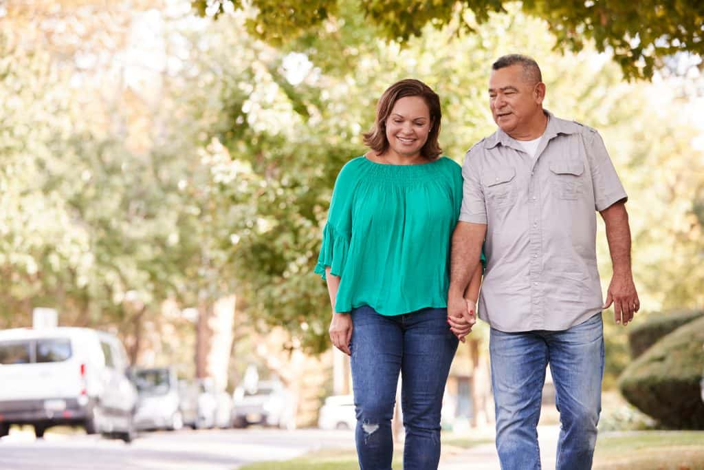 senior Couple Walking Along Suburban Street Holding Hands