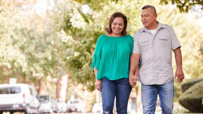 senior Couple Walking Along Suburban Street Holding Hands
