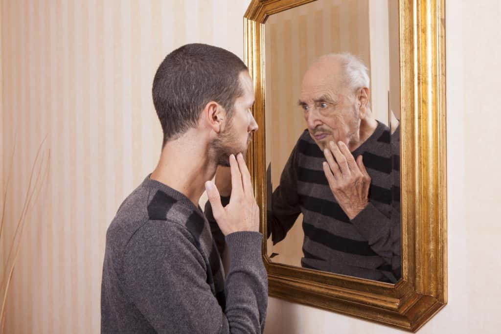 young man looking in mirror and old man looking in reflection