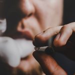 Tetrahydrocannabinol: A man smokes weed cannabis a joint and a lighter in his hands. 