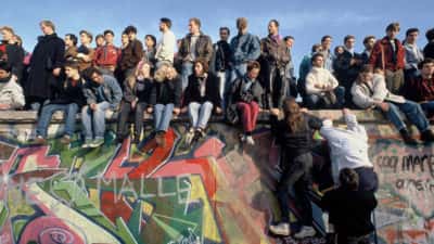 people-climb-onto-the-berlin-wall-on-november-10th-1989