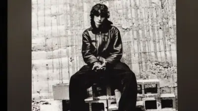 An Apple iPad displays the Spotify music streaming app. The screen the shows the song "undressed" by "Sombr" being played^ as well as the album cover art.