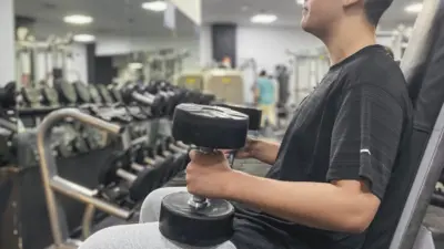 teenager-doing-weights-sitting-in-a-gymnasium