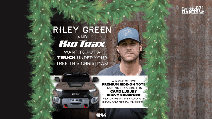 Wooden background with green christmas garland and picture of riley green with hat on Riley Green and Kid Trax want to put a truck under your tree this christmas picture of kids truck win one of five premium ride on toys from kid tax, like this camp luxury chevy colorado featuring an fm radio, usb input, and mp3 player input