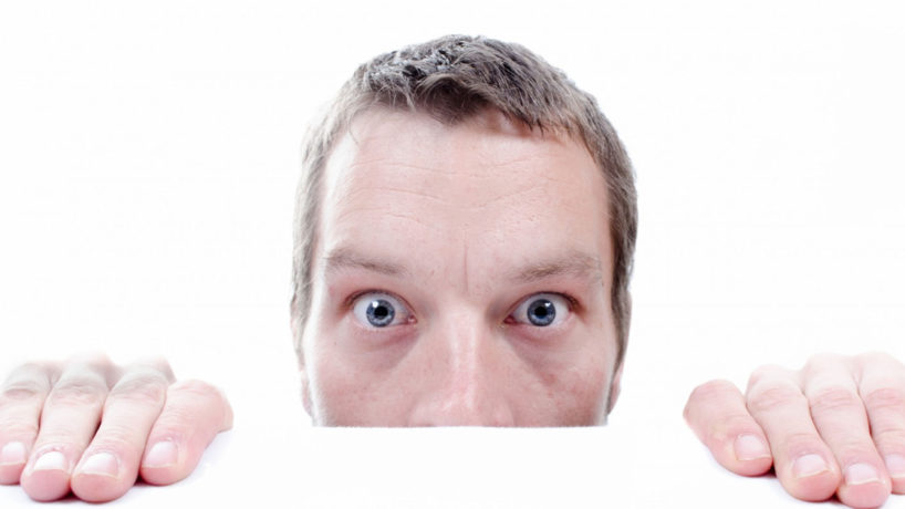 Guy peaking over the wall looking scared
