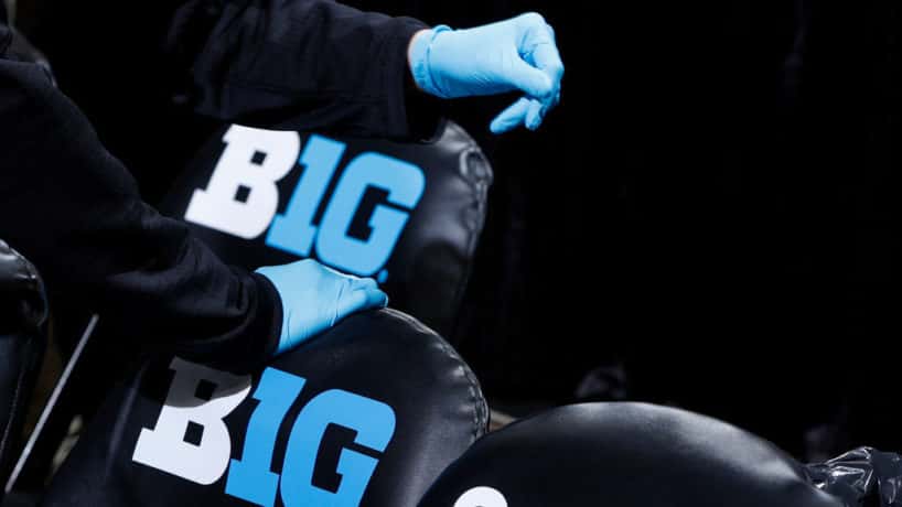 Trainers wear rubber gloves as they work in the bench area during the first round of the Big Ten Men's Basketball Tournament game between the Nebraska Cornhuskers and Indiana Hoosiers