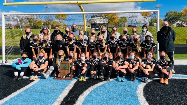 The Noblesville Girls Soccer Team poses with their coaches in front of a soccer goal