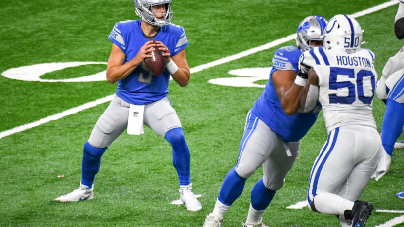 Matthew Stafford drops back to pass in a game against the Indianapolis Colts as Justin Houston drives in from the other side colliding with an offensive lineman