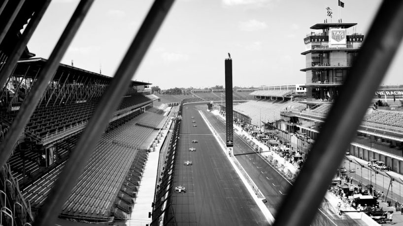 Straight away of Indinanpolis Motor Speedway with indy cars racing and no fans in the stands